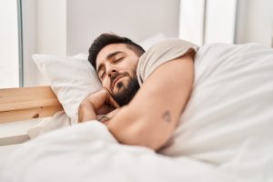 Man laying in bed during day, appears to be resting or sleeping