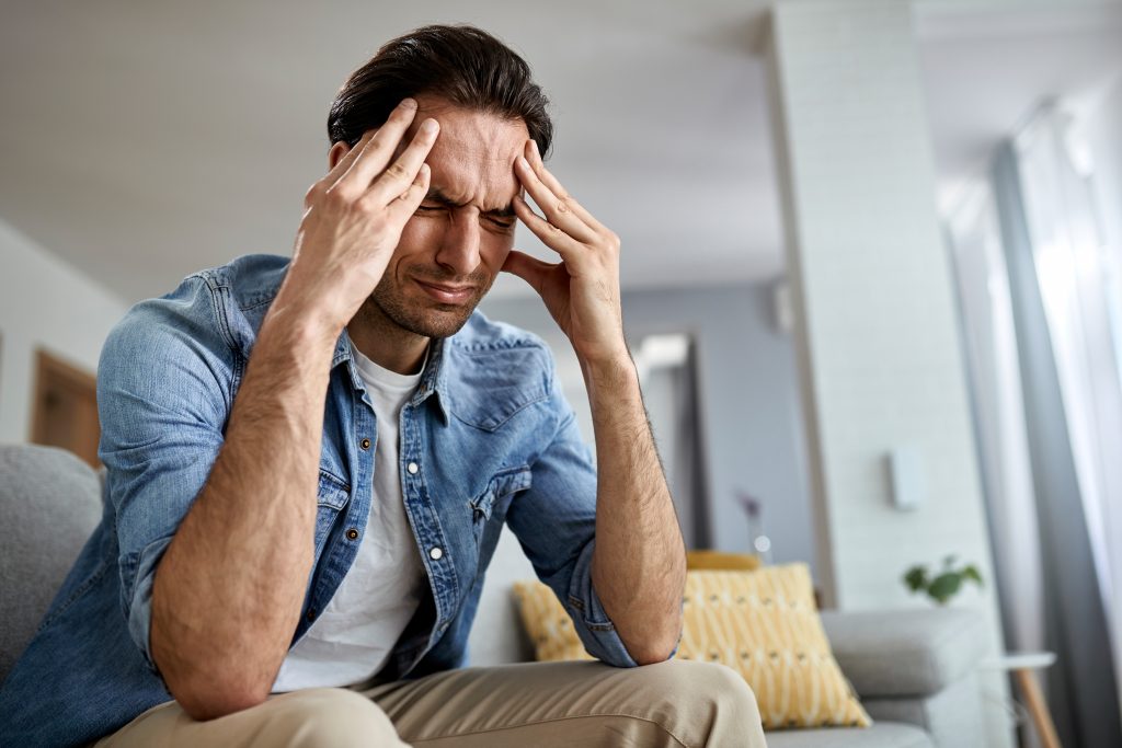 Below view of a man having a headache while being at home.