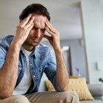 Below view of a man having a headache while being at home.